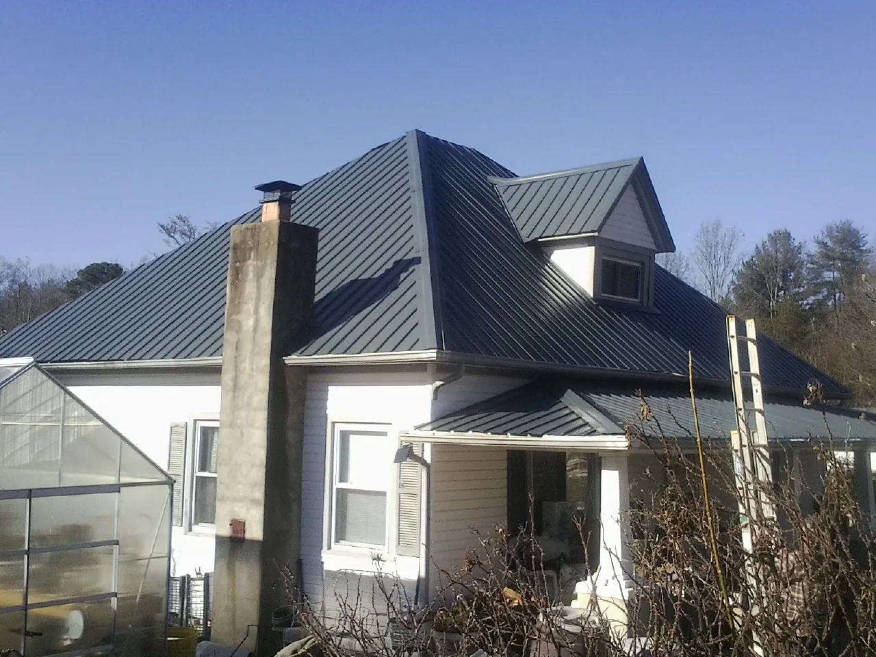 Dark blue standing seam metal roof on a white farmhouse with dormer — Slate & Tile Roof Repair by Roofing Brothers in Winamac