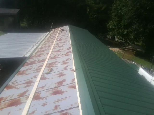 Old rusted panels beside newly installed green metal roofing — Wind Damage Roof Repair by Roofing Brothers in Winamac