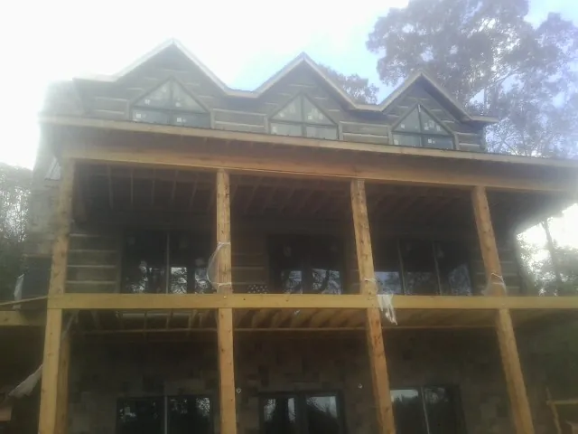 Dormers and porch framing on a large log home under construction — Roof Coating work by our crew in Winamac