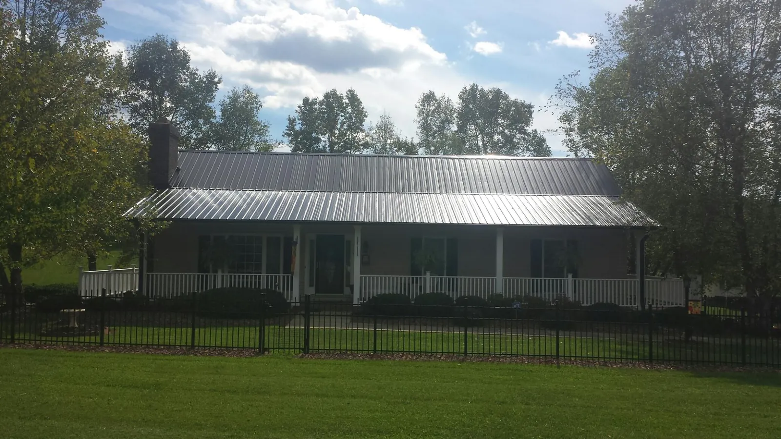 Gray metal roof on a brick ranch with a full width front porch — Gutter Guard Installation work by our crew in Winamac