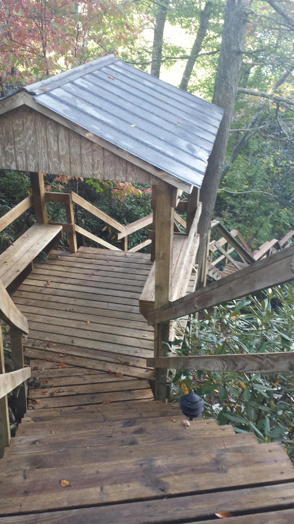 Metal roofed shelter over wooden steps on a wooded walkway — Skylight Repair & Installation work by our crew in Winamac