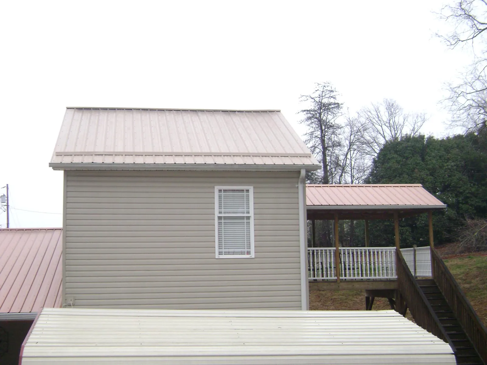 Tan metal roofs on a two story addition and attached porch, from a Roof Replacement job in Winamac
