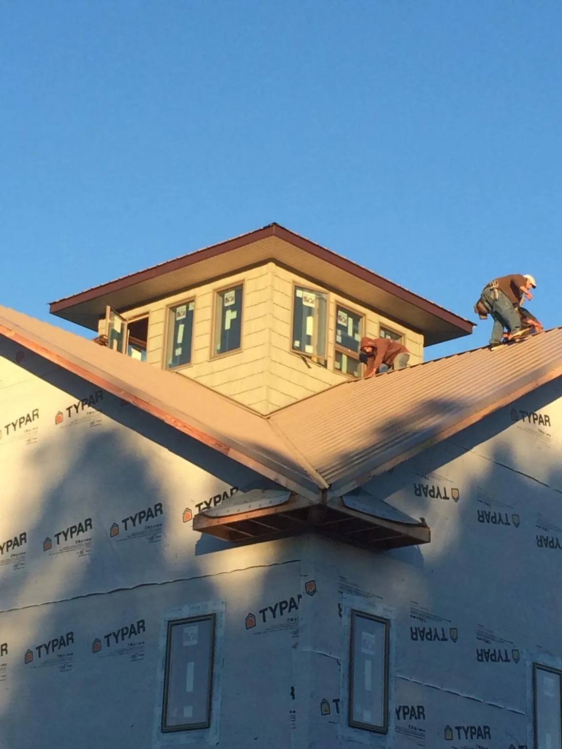 Roofers working around a rooftop cupola on a new metal roof at sunset — Roof Waterproofing in Winamac by Roofing Brothers